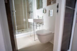 A modern bathroom with a toilet, a wall-mounted sink, and a glass-enclosed shower.